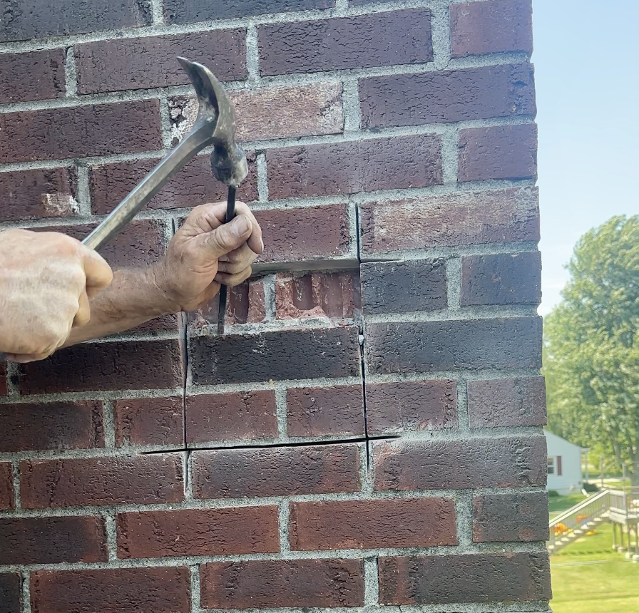 Chisel bricks to open hole in chimney to remove honeybee infestation