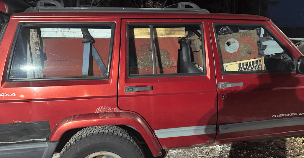 Old red Jeep Cherokee loaded with beekeeping equipment and supplies.